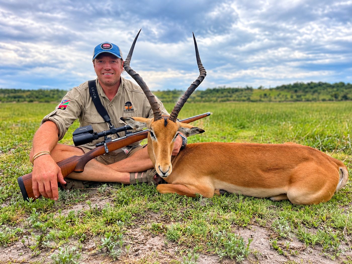 Hunter with an impala on green grass