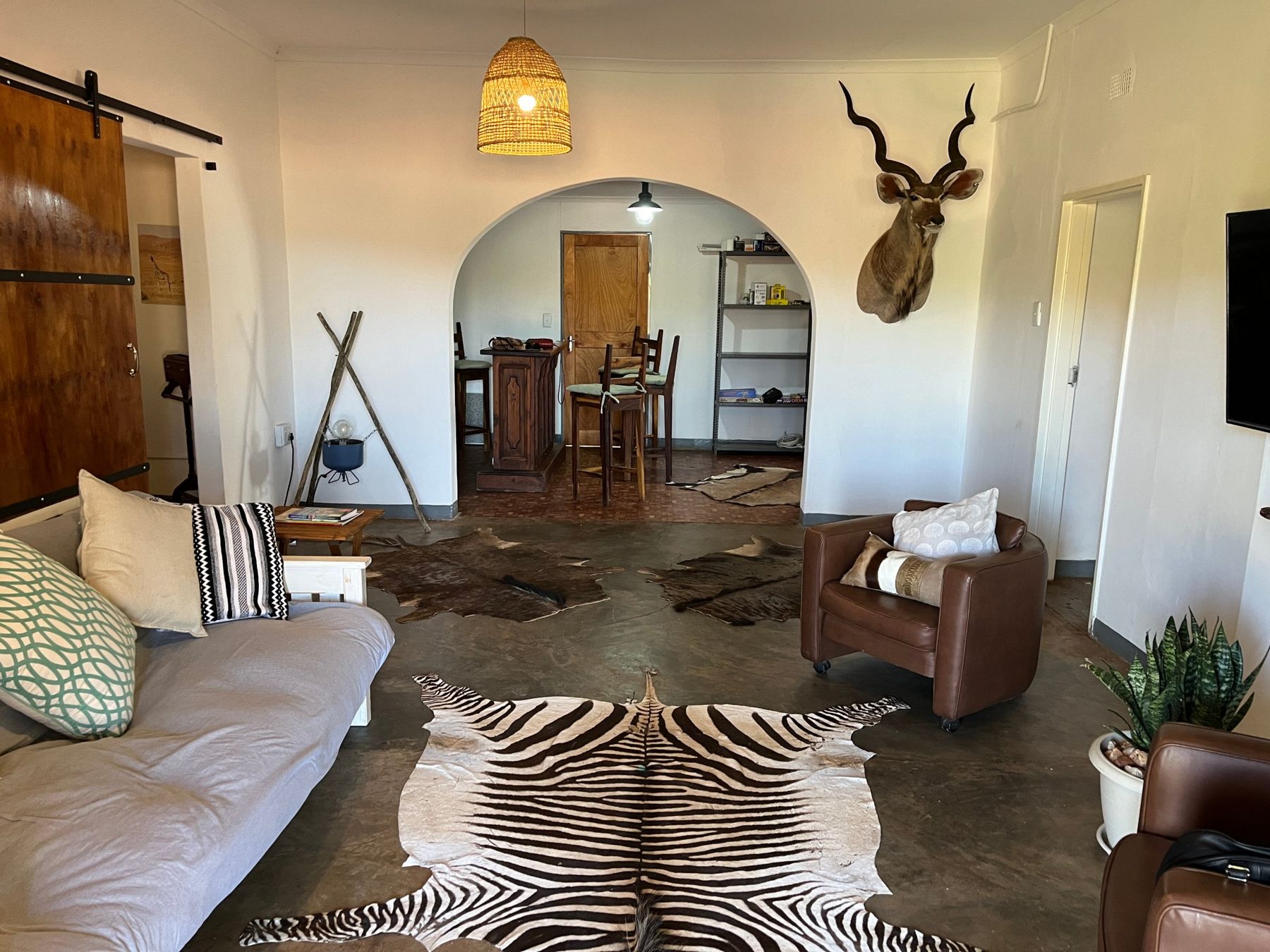 Lodge lounge with leather chairs, a kudu mount and hide rugs on a polished floor