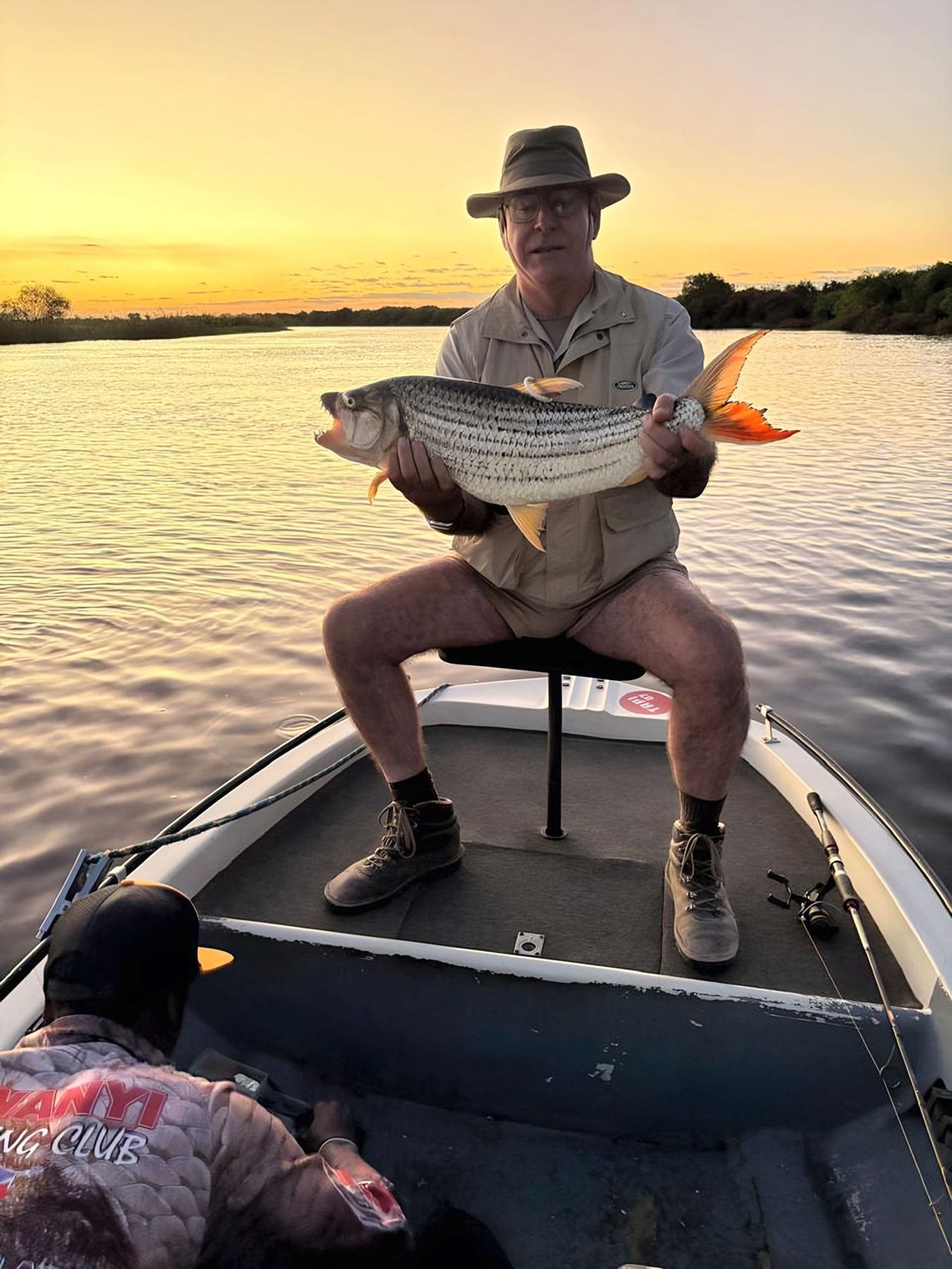 A client with a tigerfish at sunset on the river