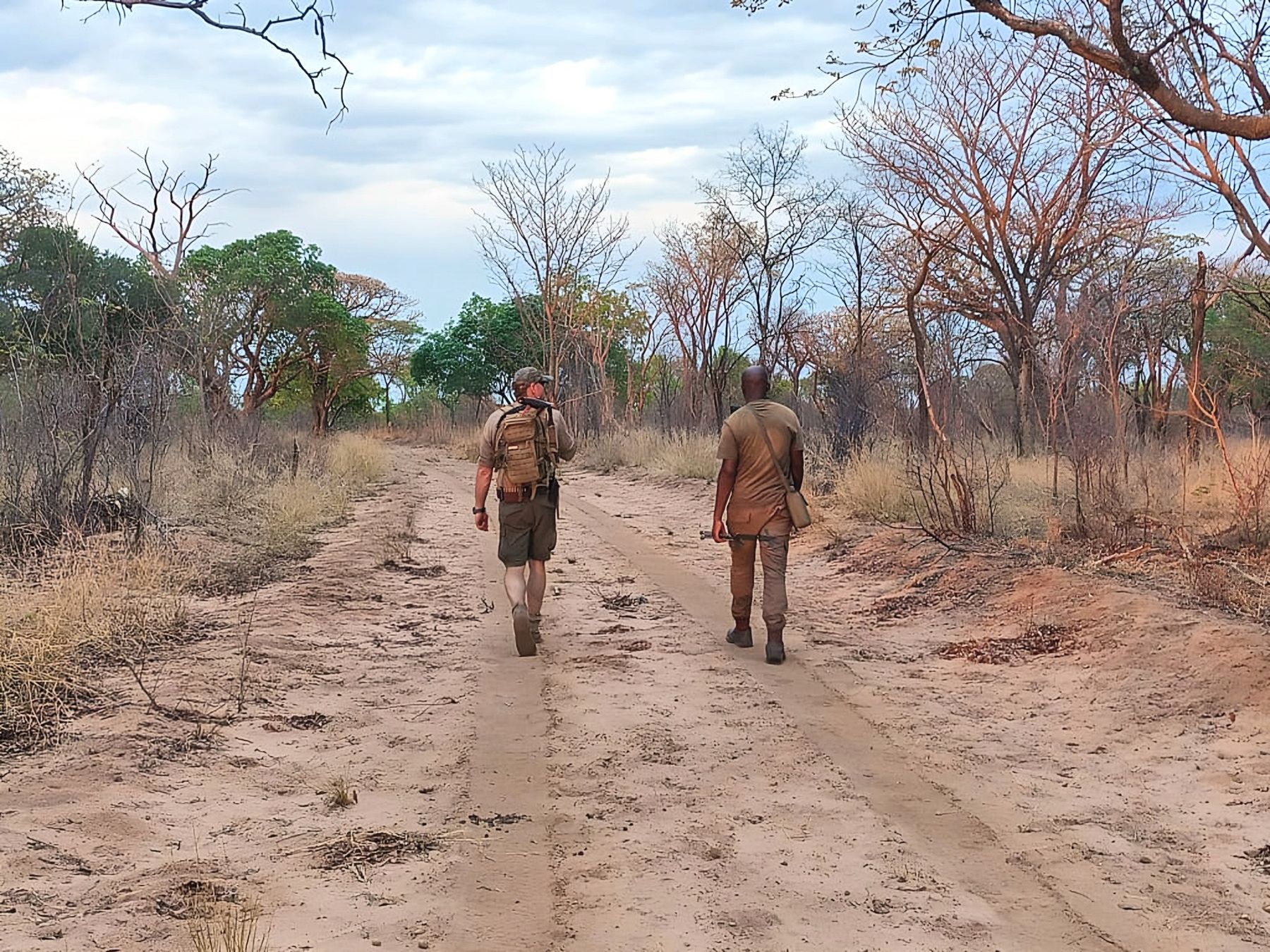 Hunter and tracker walking a sandy track